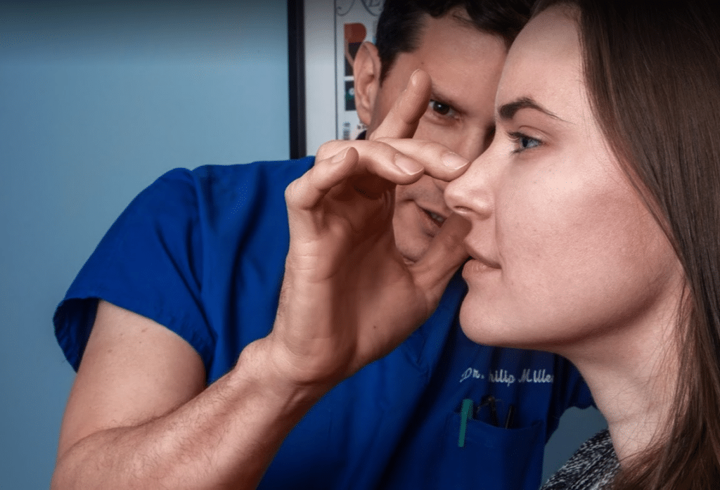 facial plastic surgeon inspecting a patient's nose for a blog about reasons to get a nose job in NYC