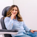 Female patient smiling and sitting in a chair at Miller Facial Plastic Surgery in New Orleans
